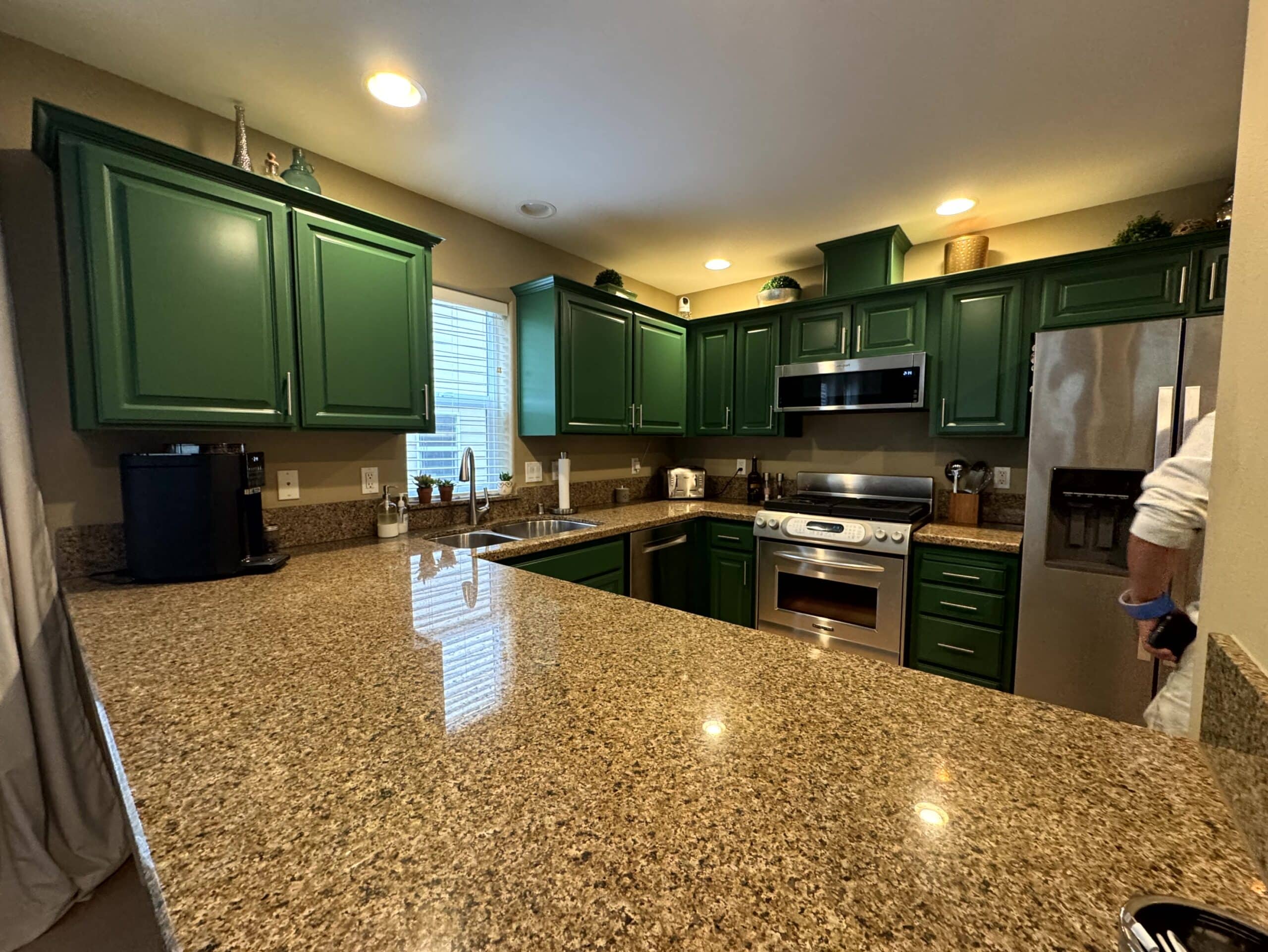 Green Painted Kitchen Cabinets Green painted kitchen cabinets with granite countertop, stainless steel appliances, and recessed ceiling lights.