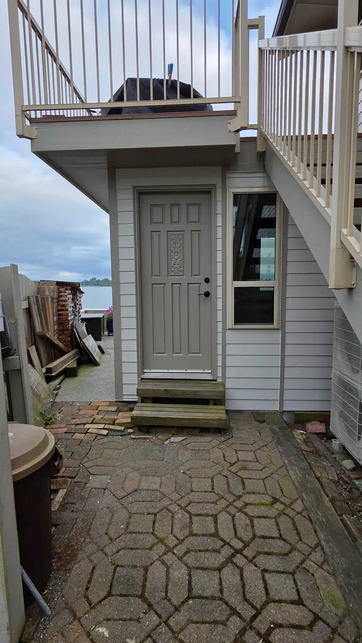 Residential Exterior Painting for a Waterfront Home Back Entrance Back entrance of a waterfront home with freshly painted gray door and white siding, leading to a patio.