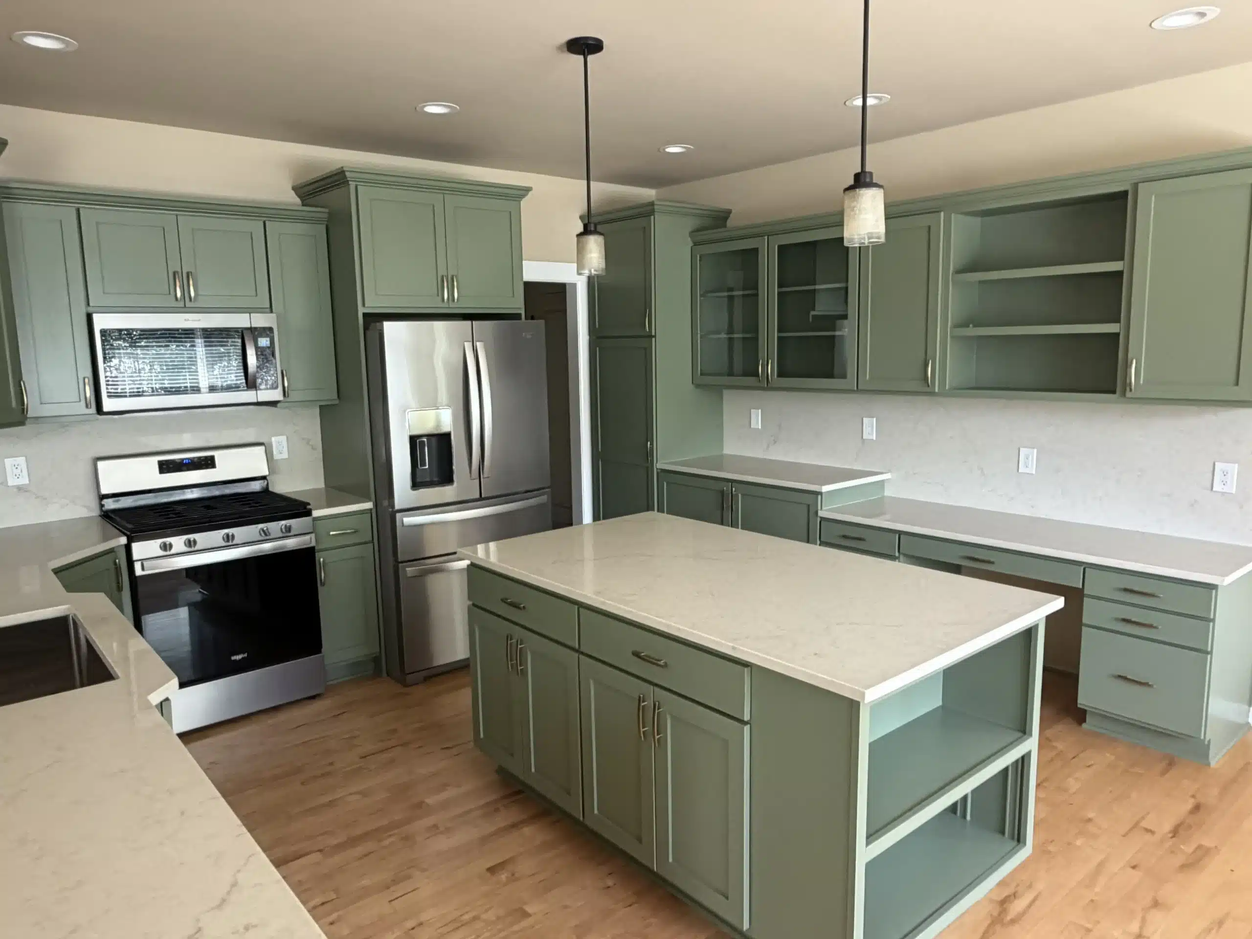 Professional kitchen cabinet painting transforms this modern space A beautifully updated kitchen featuring freshly painted green cabinets, white quartz countertops, and stainless steel appliances.