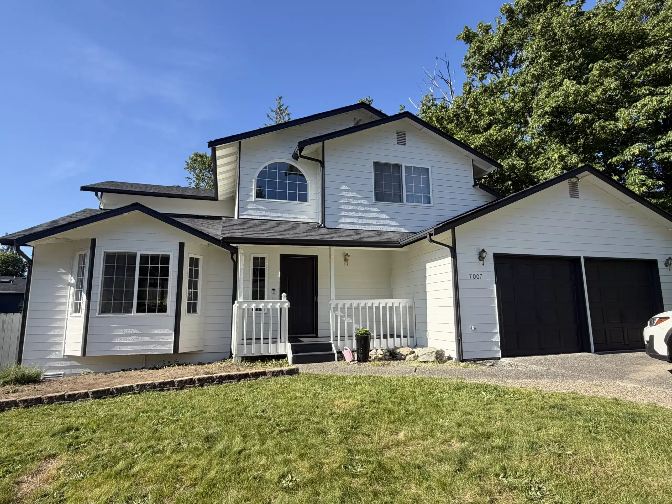 Classic White House Exterior Painting with Black Trim Expert exterior house painters completed this stunning white home with black trim and a black garage door.