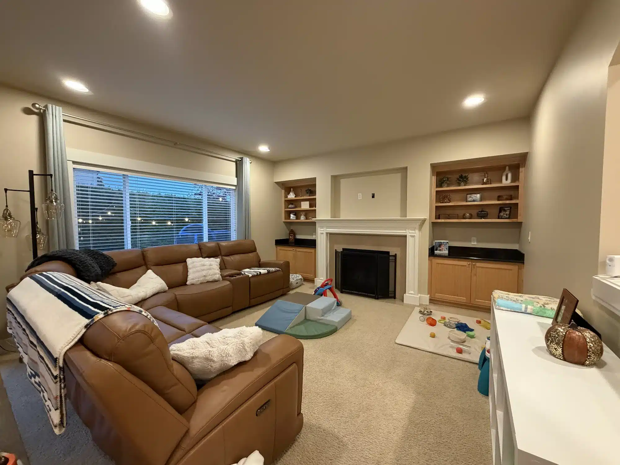 Cream Interior Residential Painting Cream-painted family room with white fireplace surround, built-in wood cabinetry, and recessed lighting in Seattle home